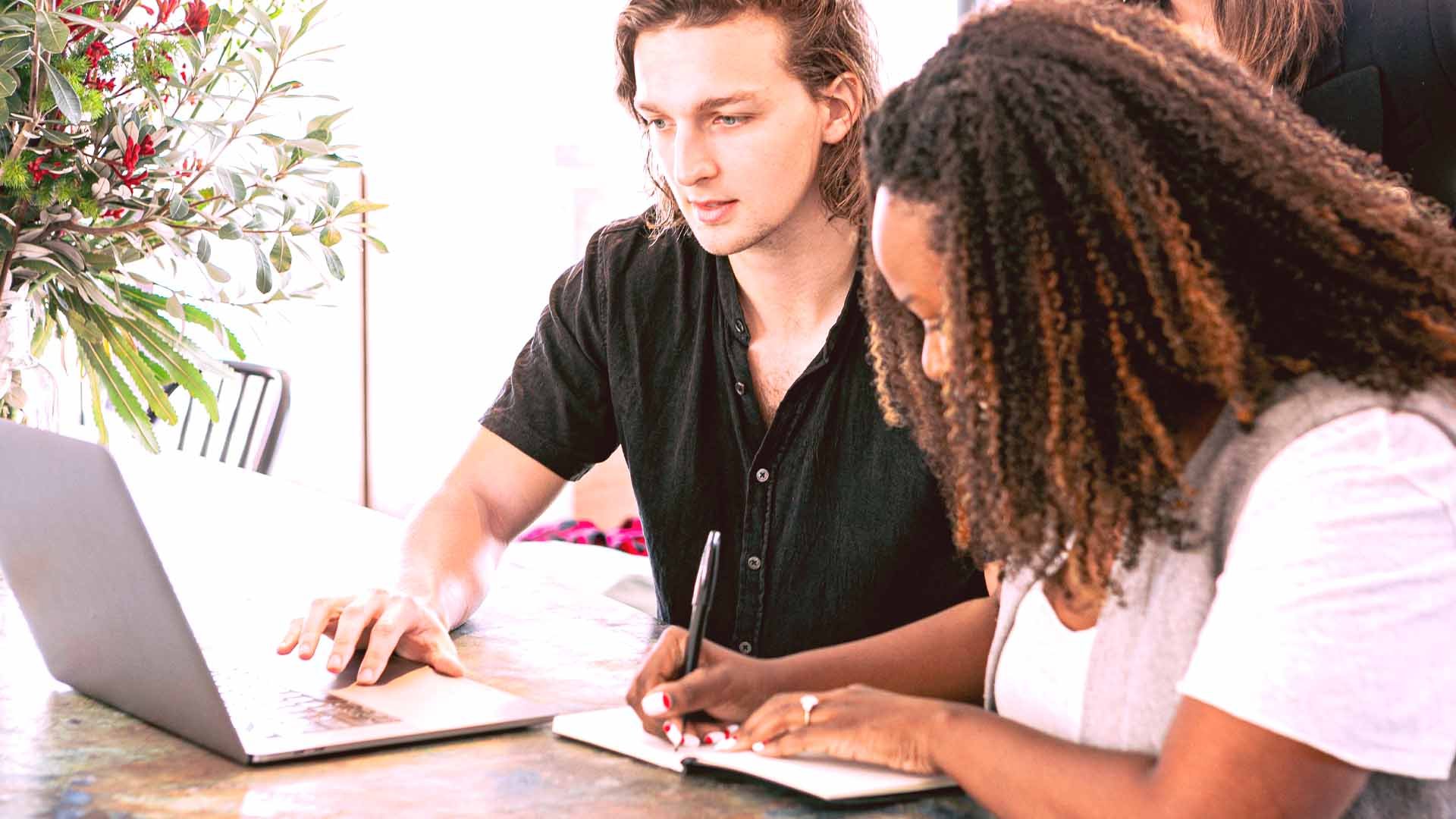 digital marketing team working on laptop and taking notes